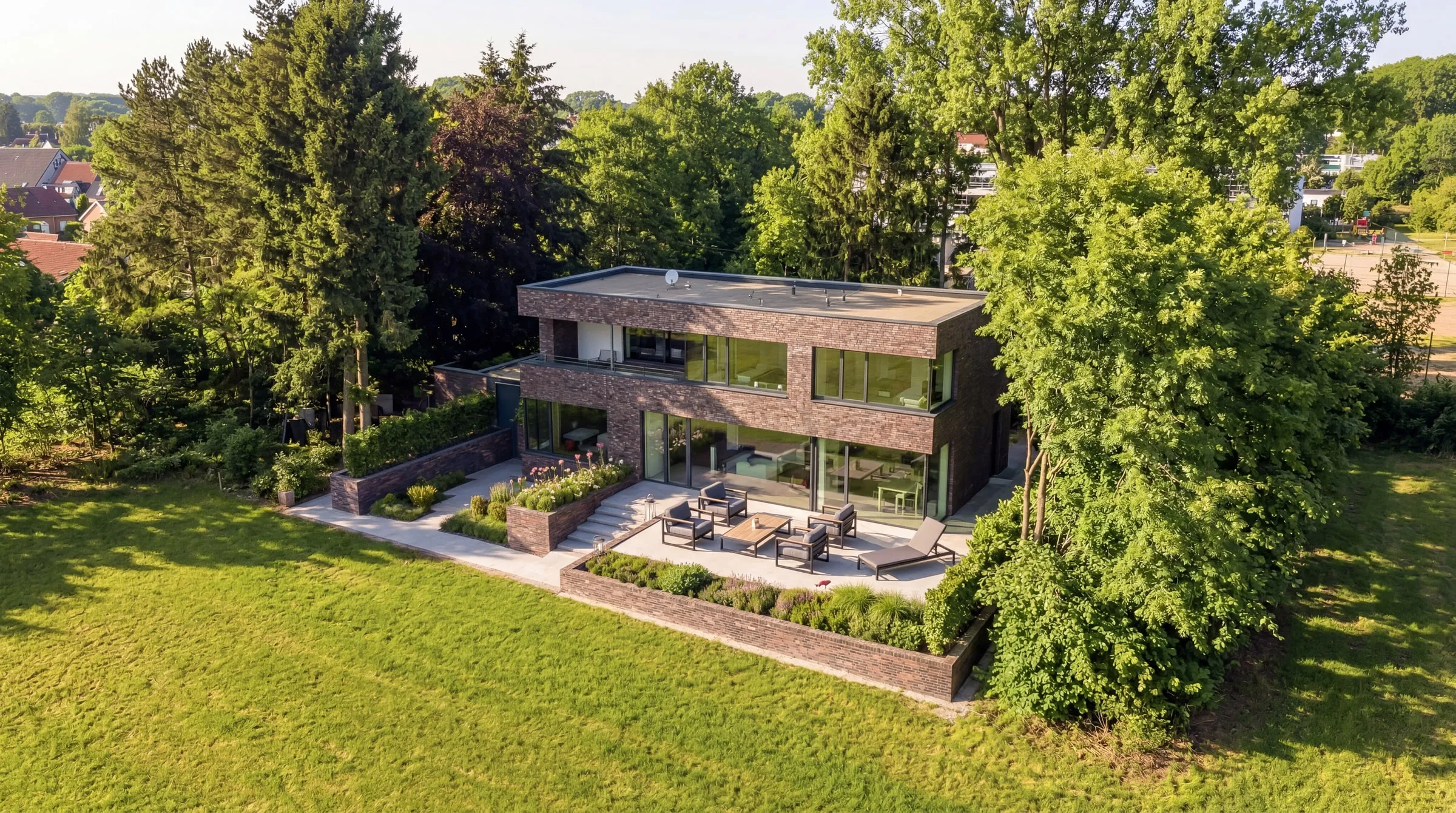 Architektur-Visualisierung aus der Drohnenperspektive: Flachdach-Villa mit Klinkerfassade und Terrasse im Grünen