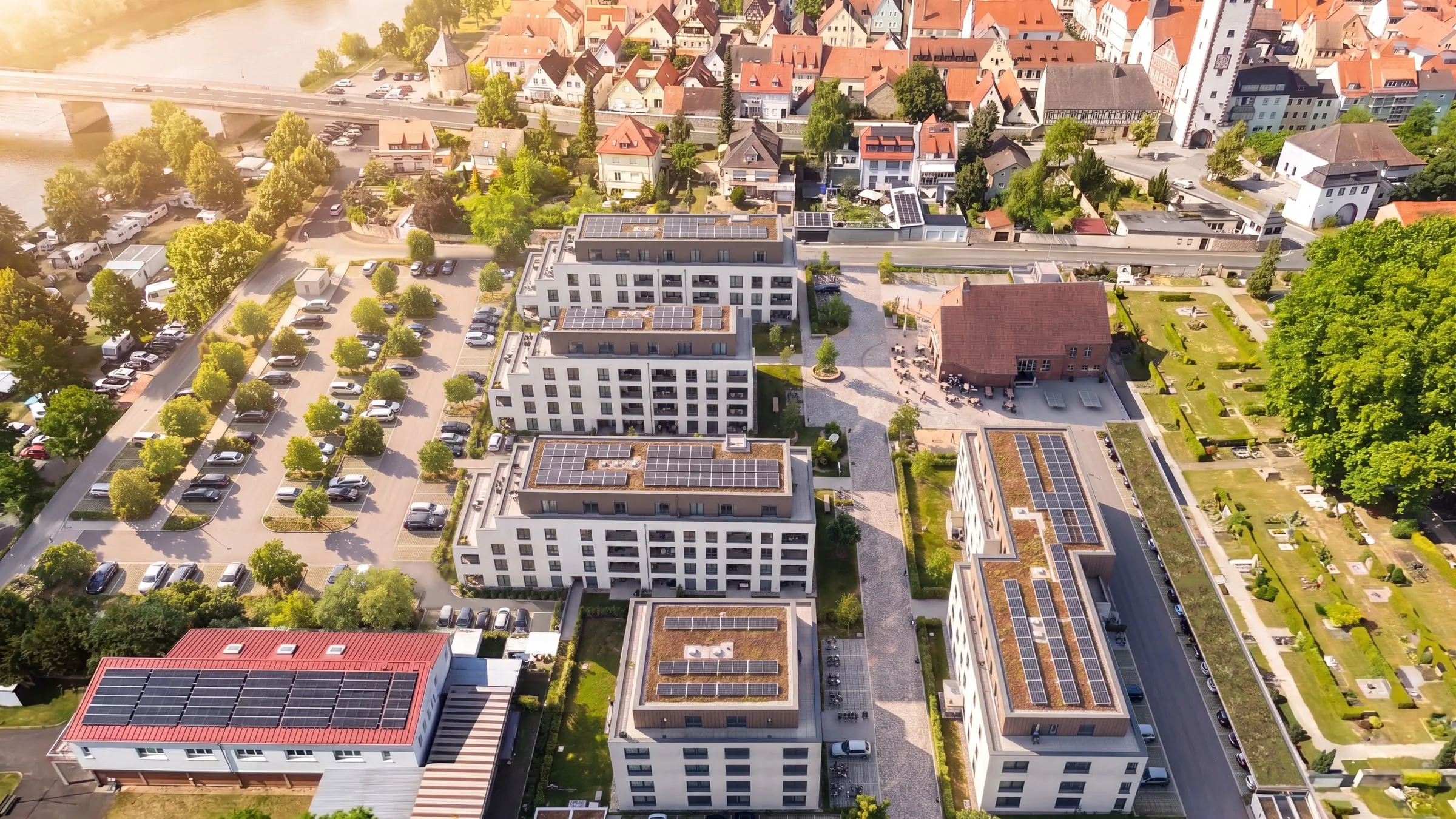 Architektur-Visualisierung als Luftbild: neues Wohnquartier mit mehreren Mehrfamilienhäusern, eingebettet in die reale Umgebung