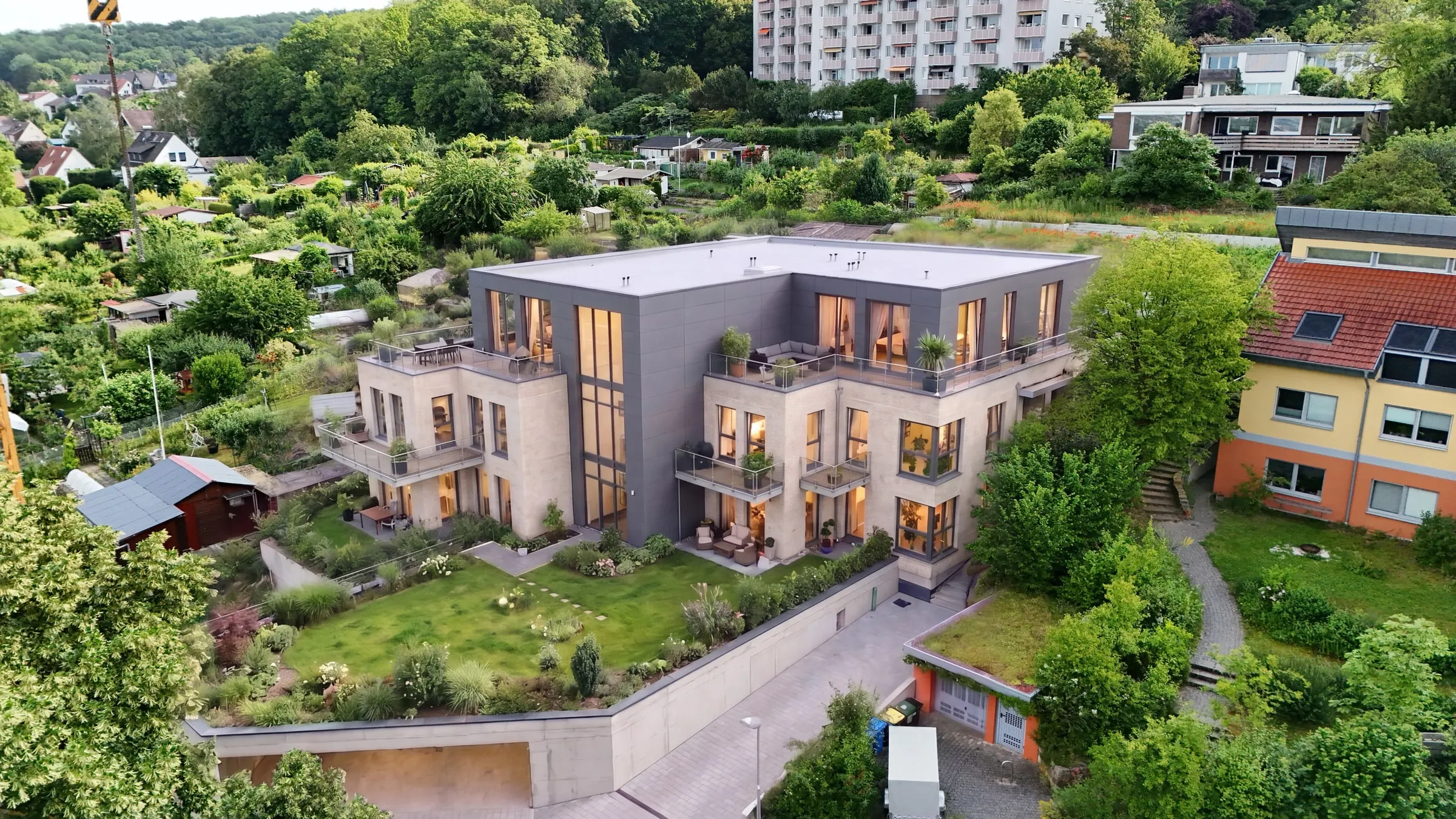 Drohnenbild-Compositing: Mehrfamilienhaus mit Flachdach und Dachterrassen in der bestehenden Nachbarschaft