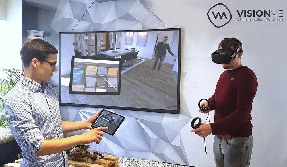 Visionme Geschäftsführer Florian Wenk und Dennis Dohmeier präsentieren den Immobilien Designer auf VR-Brille und Tablet mit Beamer im Hintergrund